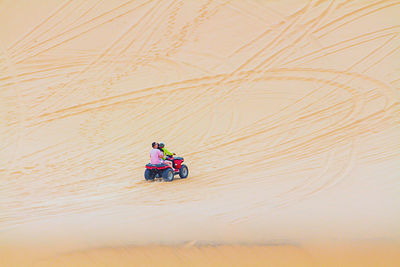 High angle view of woman riding motorcycle on sand