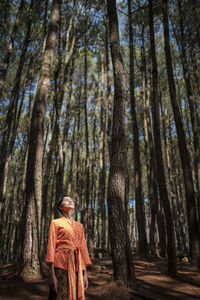 Woman standing against trees in forest