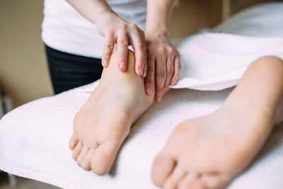 The masseur gives a massage to the female feet at the spa.