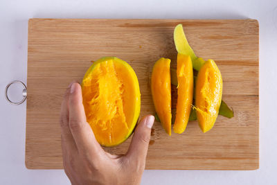 Midsection of woman holding orange on cutting board