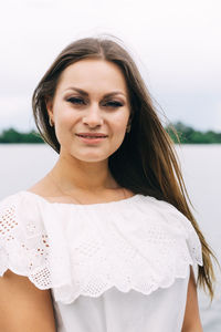 Portrait of young woman standing against sky