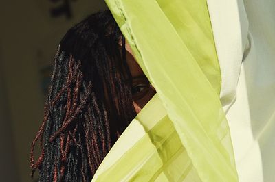 Portrait of playful woman hiding behind curtain