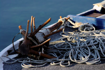 Wooden anchor tied by rope on boat over lake
