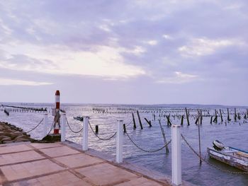 Wooden posts in sea against sky