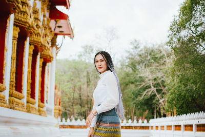 Side view of woman standing against trees