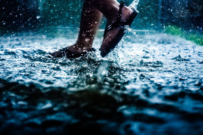 Low section of person running in water during rainfall