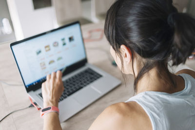 High angle view of woman sitting by laptop over table