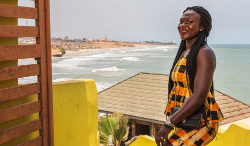 African woman dressed in colorful ghanaian clothes standing on a hill overlooking the accra coast