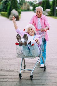 Portrait of smiling young woman holding miniature shopping cart on table