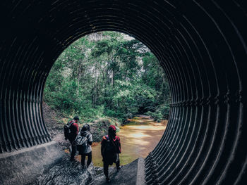 People exploring the drainage tunnel into the rainforest