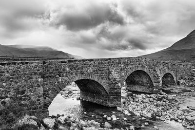 Arch bridge over mountains against sky