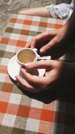 Midsection of woman holding coffee cup on table