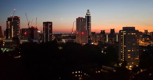 Illuminated buildings in city against sky at night