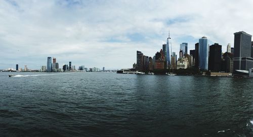 Sea by modern buildings in city against sky