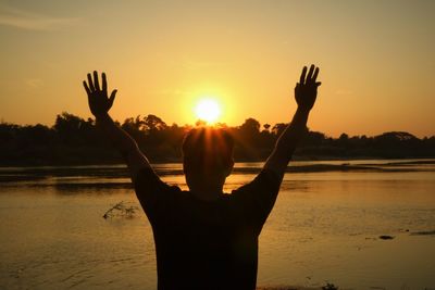 Silhouette woman hand at beach during sunset