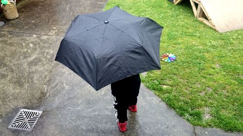 High angle view of child with umbrella walking on footpath