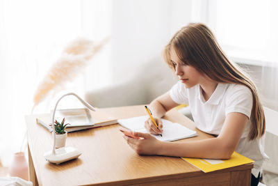 A beautiful girl is sitting at a table and preparing 