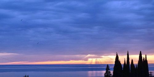 Scenic view of sea against cloudy sky at sunset