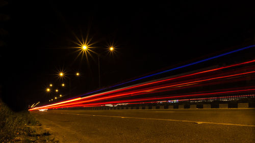 Light trails on road against sky at night