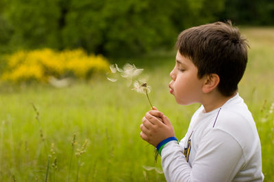Boy blowing dandelion on field