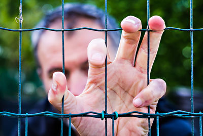 Close-up of hands holding fence