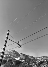 Low angle view of cables by mountains against clear sky