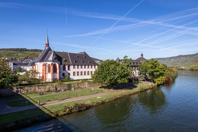 View of building by river against blue sky