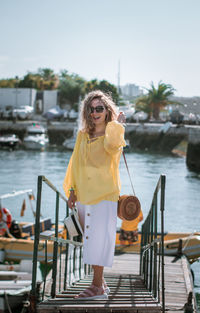 Full length of woman standing on jetty by river against sky