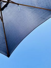 Low angle view of umbrella against clear blue sky
