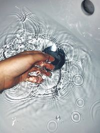 High angle view of human hand in bathroom sink