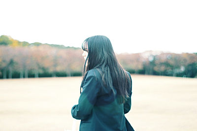 Side view of woman standing against sky during winter
