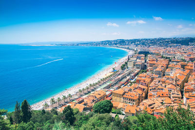 High angle view of townscape by sea against blue sky