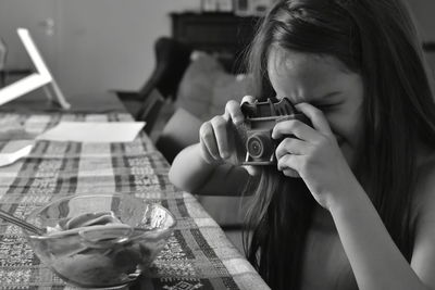 Cute girl photographing food on table