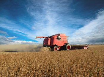 Combine harvester on field against sky