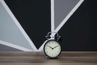 Close-up of alarm clock on table against wall