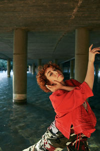 Curly redhead young female dancing with red jacket