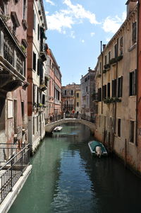 Canal amidst buildings in city against sky