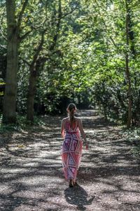 Rear view of woman walking on footpath in forest