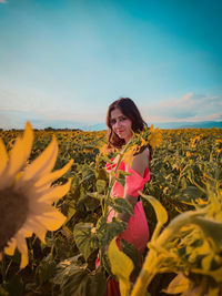 Portrait of young woman standing amidst sunflowers