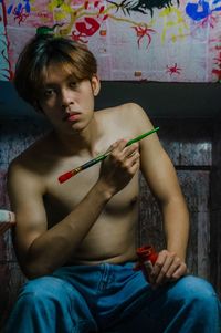Young man holding paintbrush and looking at the camera