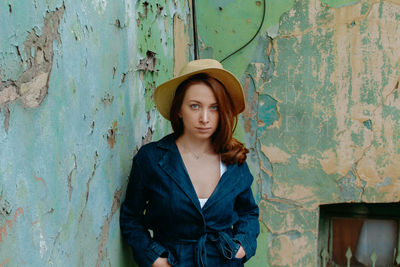 Portrait of young woman standing against wall