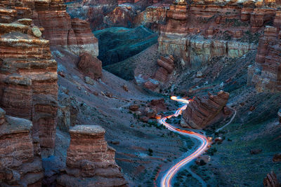 Aerial view of light trails on road amidst rock formations in desert