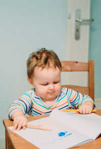 Cute boy sitting on table at home