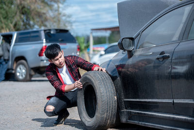 Portrait of man with car on road