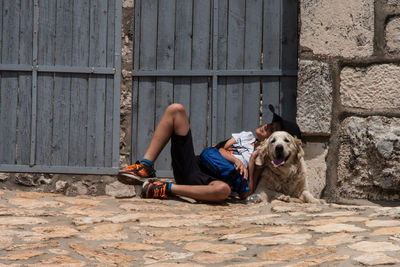 Boy resting with pet by gate