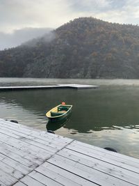 Boat moored on lake against sky