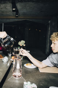 Cropped hand of young businessman pouring coffee for coworker in office