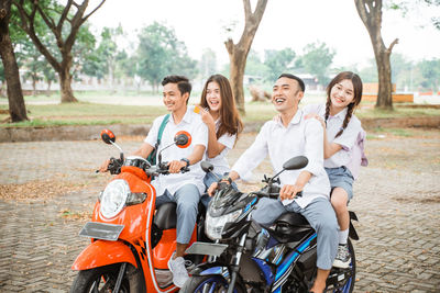 Portrait of smiling friends with bicycles on road