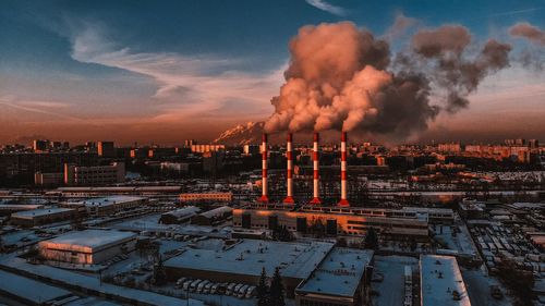 Smoke emitting from factory against sky