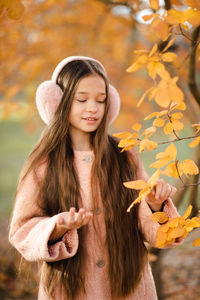 Cute kid girl 10-12 year old with long blonde hair wear headband earphones with yellow autumn leaves